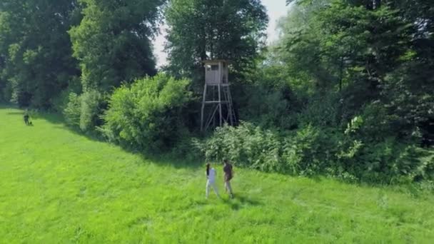 Ein Pärchen und ein Jäger spazieren im grünen Rasen — Stockvideo