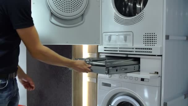 Eine Person prüft Waschmaschine in der Küche lagern Eine Person prüft Waschmaschine in der Küche lagern