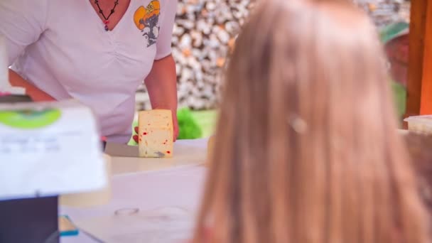 Vendedor está cortando un queso en feria rústica — Vídeos de Stock