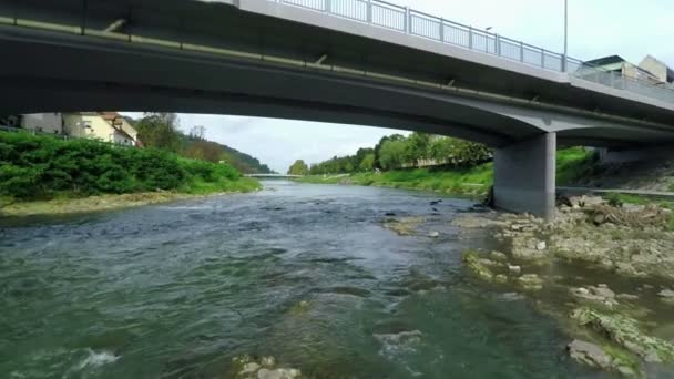 Rivier die onder een brug loopt met een hoofdstraat — Stockvideo