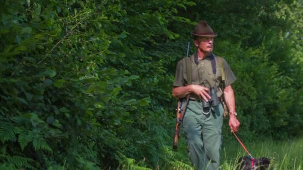 Hunter en zijn hond lopen langs het bos — Stockvideo