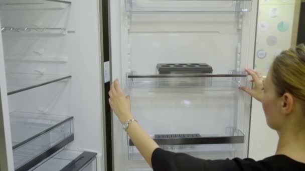 Uma pessoa inspeciona a geladeira na loja da cozinha — Vídeo de Stock