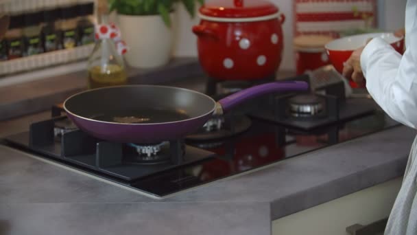 Cocina poniendo comida en la sartén — Vídeos de Stock