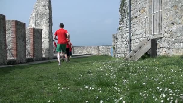 Team of people running through castle ruins — Stock Video
