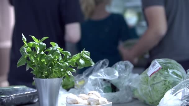 Είδη παντοπωλείου lay στον πάγκο της κουζίνας με τους ανθρώπους στην πλάτη — Αρχείο Βίντεο