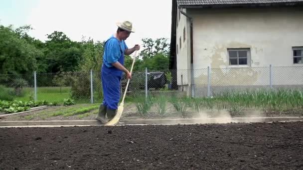 Kweker gebruikt de bezem te reinigen van de tuin — Stockvideo