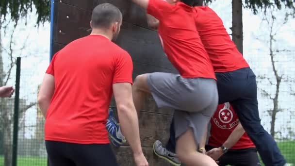 Equipo de personas que se ayudan mutuamente a saltar sobre los obstáculos — Vídeo de stock