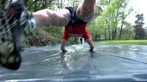 Людина ковзання вниз водною гіркою на смугу перешкод — стокове відео