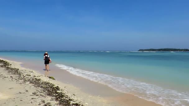 Жінка ходить по красивому бірюзовому морю — стокове відео
