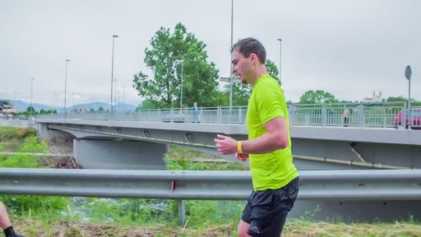 Hombre corriendo cerca de río y puente — Vídeos de Stock