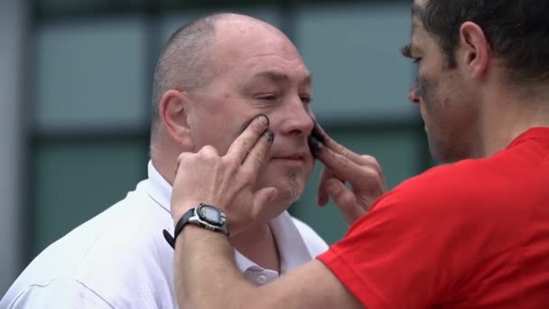 Hombre pintando la cara de otro hombre — Vídeos de Stock