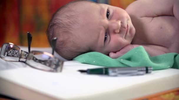 Baby liggend op een boek — Stockvideo