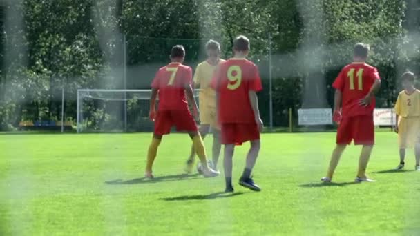 Jugendliche spielen Fußball an einem sonnigen Tag — Stockvideo