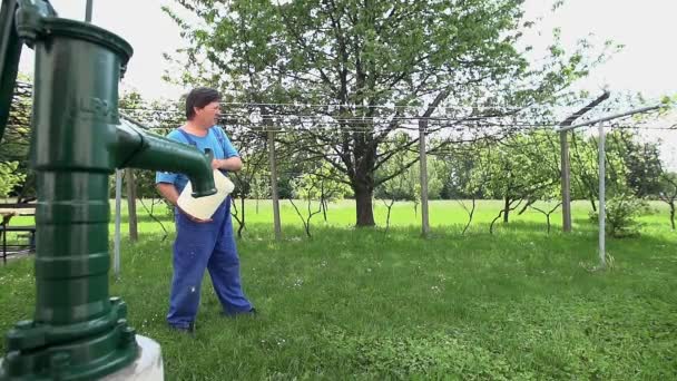 Spatten van het water uit de container in het gras — Stockvideo