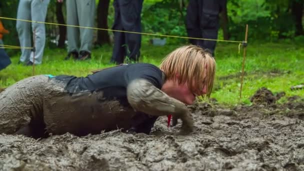 장애물 코스의 일환으로 진흙을 통해 크롤 링 하는 여자 — 비디오