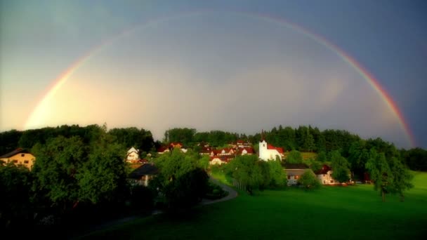 Arco iris que se colocan sobre la pequeña aldea — Vídeos de Stock