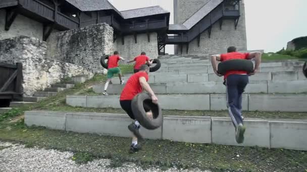 Team of people running up the stairs and carrying tires — Stock Video