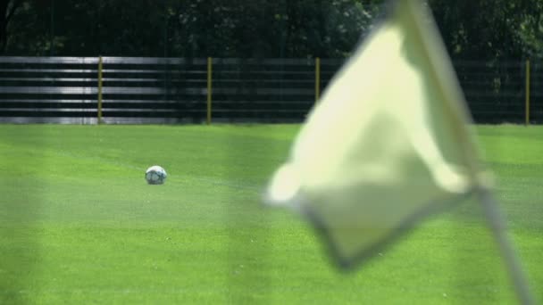 Bandera ondeando en el campo de fútbol con foco en la pelota — Vídeos de Stock