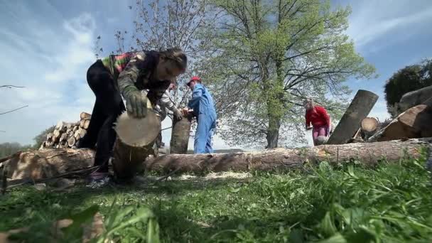 Young woman trying to pick up heavy log — Stock Video