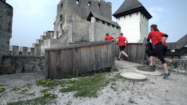 Equipe que corre sobre ponte de madeira do castelo — Vídeo de Stock