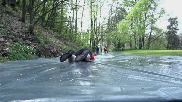 Людина ковзання вниз водною гіркою на смугу перешкод — стокове відео