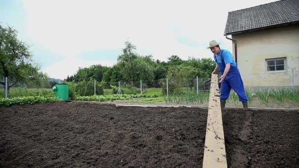 Садовник с помощью деревянных грабли — стоковое видео