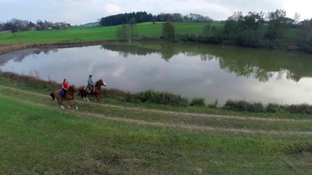 Casal montando os cavalos no galope perto do lago — Vídeo de Stock