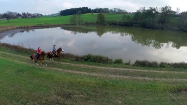 Paar reitet mit Pferden im Galopp am See