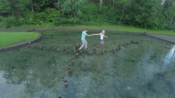 couple marchant sur des souches dans l'eau 