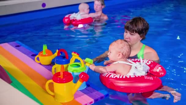 Enfants nageant avec des mères dans la piscine — Video