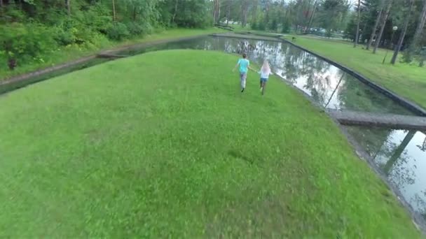 Junge und Mädchen rennen durch einen Park — Stockvideo