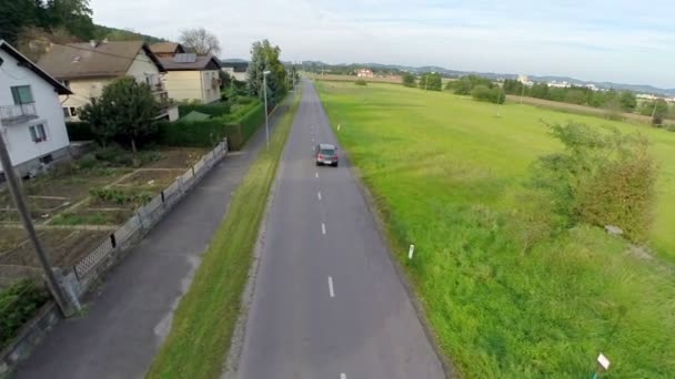 Coche que conduce en una avenida de la autopista cerca de casas — Vídeo de stock