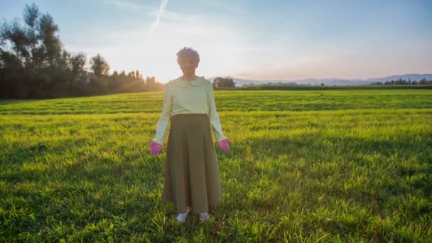 Viejo abuelita de pie en el césped con puesta de sol — Vídeos de Stock