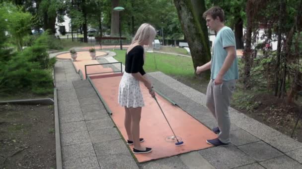 Пара, играющая в мини гольф — стоковое видео