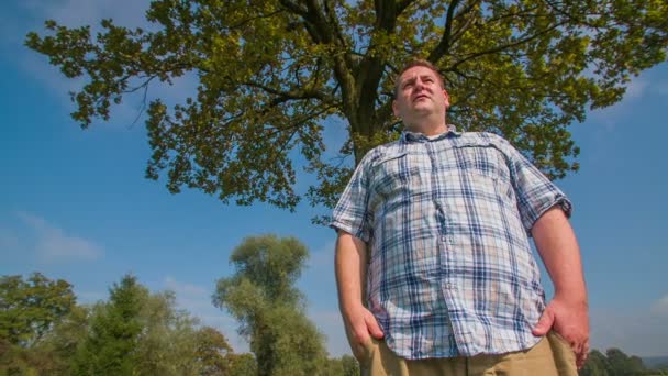 Gros désossé homme debout sous un arbre — Video