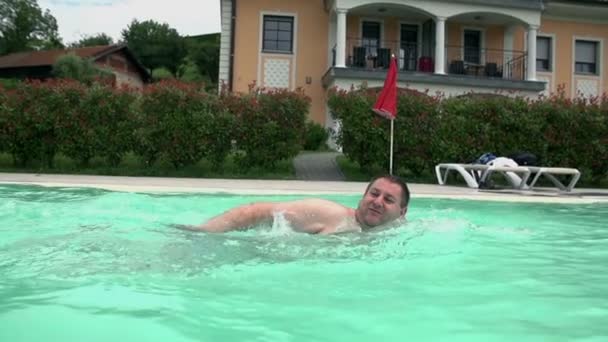 Hombre nadando en una piscina junto a la casa — Vídeo de stock