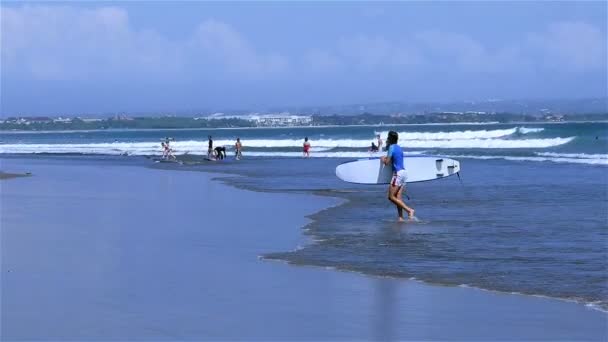 Surfer lopen van zee aan zandstrand — Stockvideo