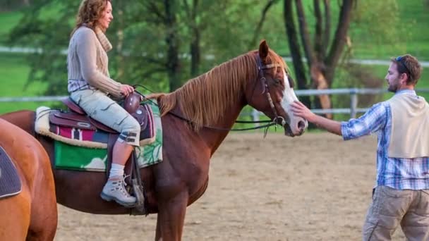 Мужчина помогает женщине слезть с лошади — стоковое видео