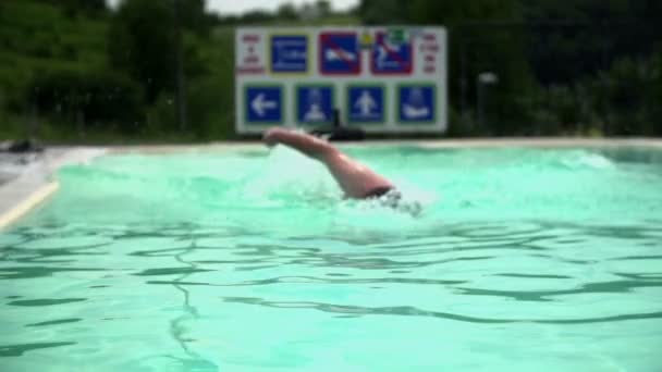 Мужчина плавает в бассейне возле дома — стоковое видео