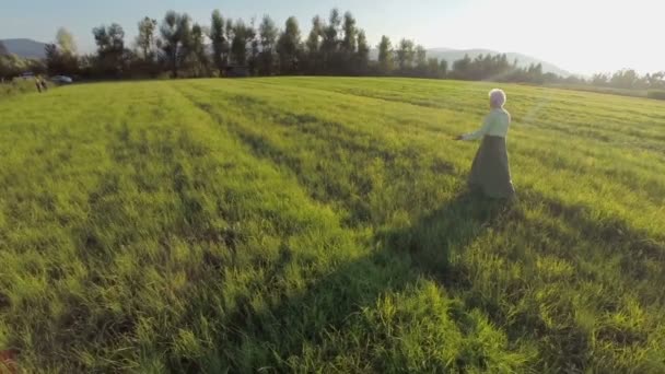 Стара жінка ходить на промені заходу сонця — стокове відео