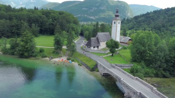 Iglesia junto a un lago con puente medieval — Vídeo de stock