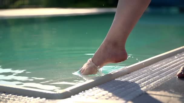 Женская нога поднимает волны на поверхности воды — стоковое видео
