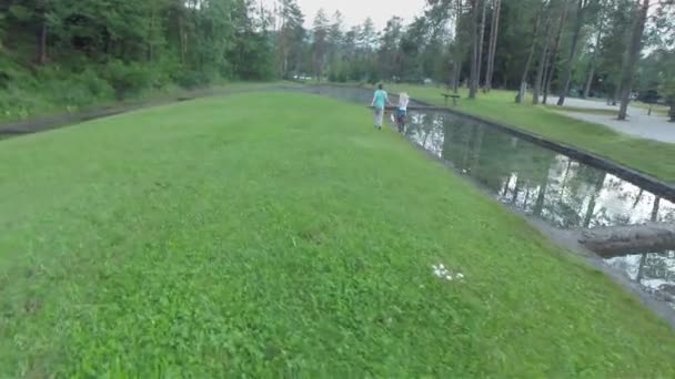 Пара работает на зеленом поле с озером — стоковое видео