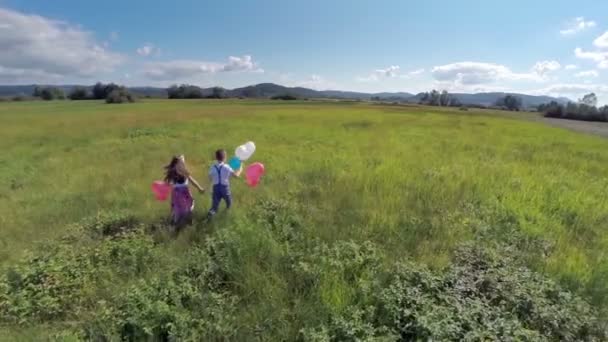 Двое детей бегают с воздушными шарами — стоковое видео