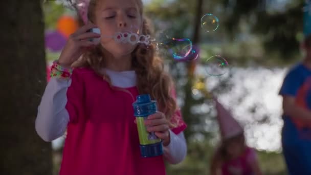 Op de out waait deur verjaardagspartij het meisje de bubbels — Stockvideo