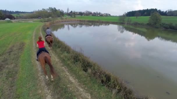 Casal montando os cavalos em galope perto do lago — Vídeo de Stock