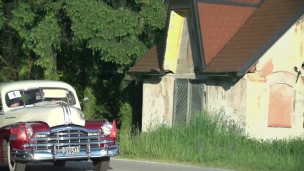 Vintage car rolling by old house — стоковое видео