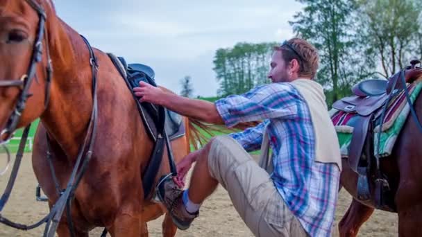 El hombre se sube a un caballo para empezar una lección — Vídeos de Stock