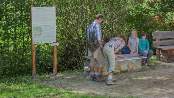 Paar komt naar de bank waar de kinderen spelen — Stockvideo