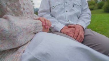 bir bankta oturan çift ve ellerini birlikte katıldı